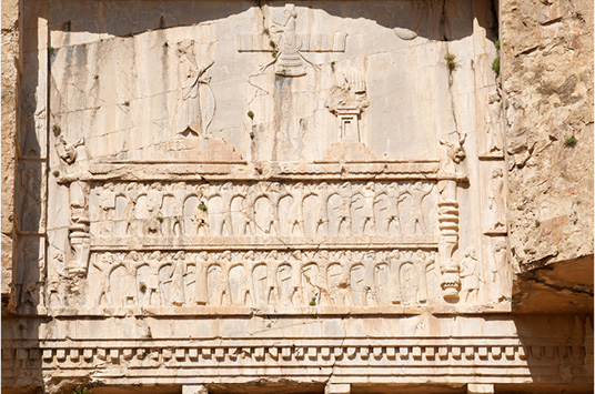PLATE III. King saluting the winged disk; thought to be the tomb of Xerxes I (r. 485-465 BCE) at Naqš-e Rostam, top register. Photograph by A. Davey, licensed under CC-by-2.0 Generic.
